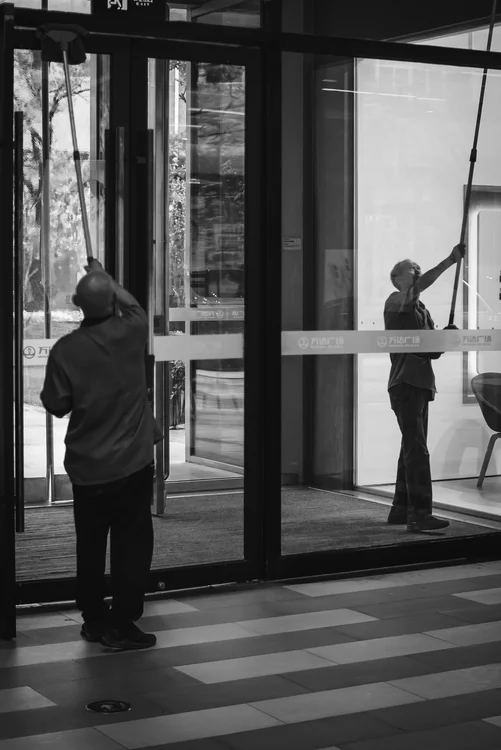 Janitors cleaning glass doors at a commercial building